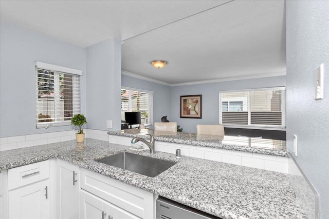 kitchen featuring a sink, light stone counters, crown molding, and white cabinets