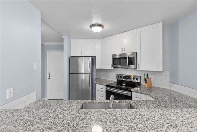 kitchen with light stone counters, a sink, stainless steel appliances, white cabinetry, and decorative backsplash