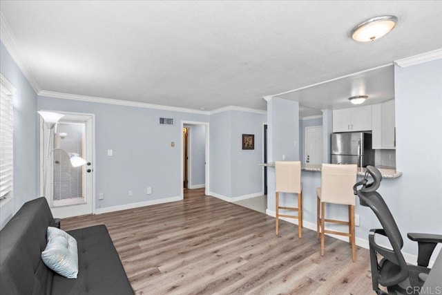 living room featuring visible vents, ornamental molding, and light wood-style floors