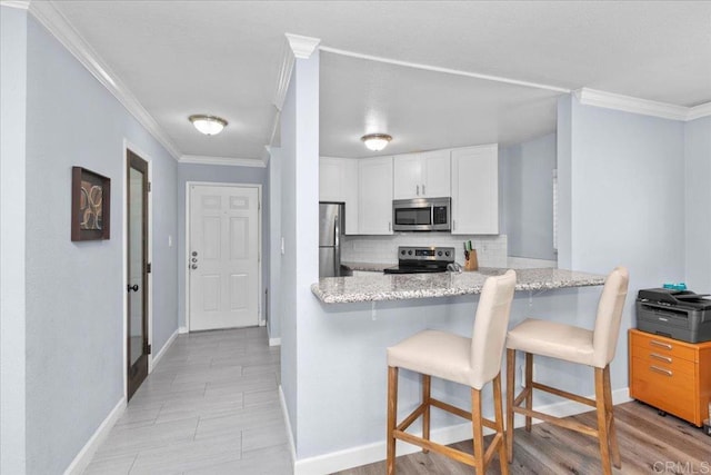 kitchen featuring white cabinets, crown molding, appliances with stainless steel finishes, baseboards, and decorative backsplash