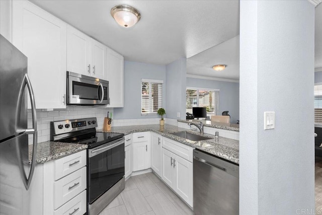 kitchen featuring a sink, appliances with stainless steel finishes, crown molding, and light stone counters