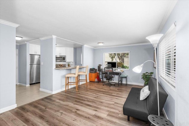 home office with crown molding, baseboards, and light wood-type flooring
