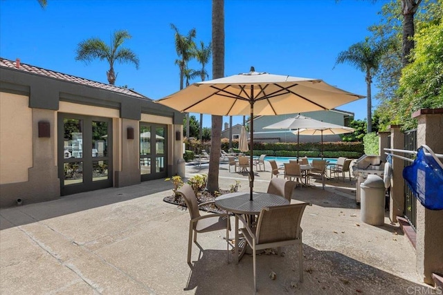 view of patio / terrace with french doors, outdoor dining space, and an outdoor pool