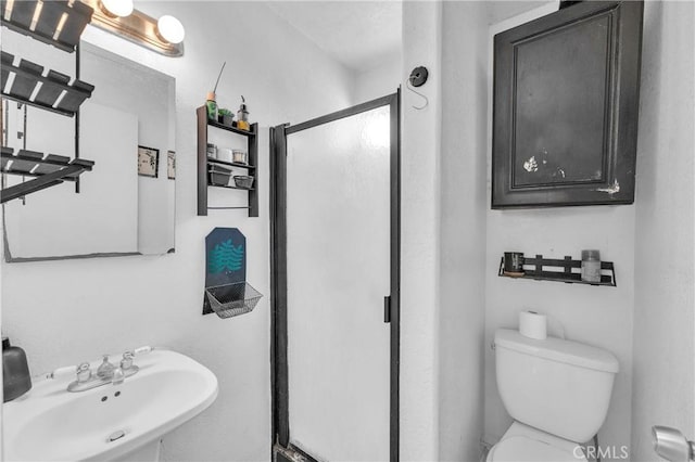 bathroom with a sink, a shower stall, and toilet