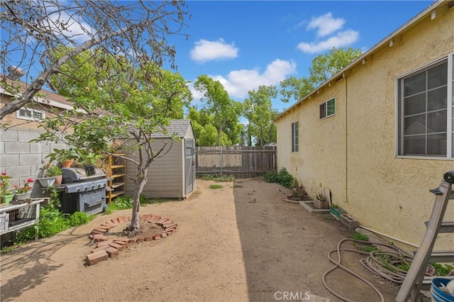 view of yard with a fenced backyard, an outbuilding, and a storage shed