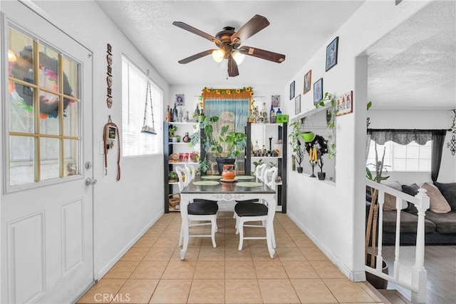 dining space with baseboards, a textured ceiling, ceiling fan, and a wealth of natural light
