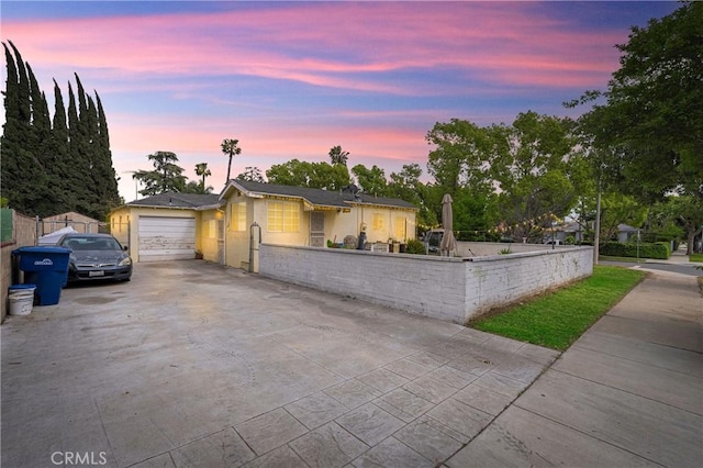 view of front facade featuring an attached garage, driveway, a fenced front yard, and stucco siding