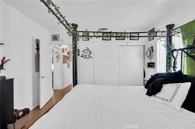 bedroom featuring baseboards, visible vents, wood finished floors, and a closet