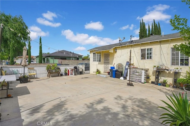 rear view of property with a patio, stucco siding, and fence