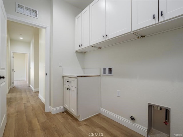 laundry room with visible vents, cabinet space, light wood finished floors, and baseboards