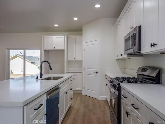 kitchen featuring stainless steel appliances, white cabinetry, a sink, and light wood finished floors