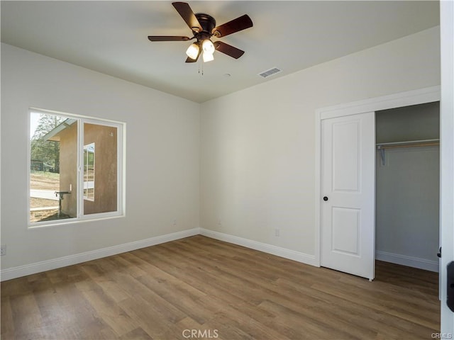 unfurnished bedroom featuring baseboards, wood finished floors, and visible vents