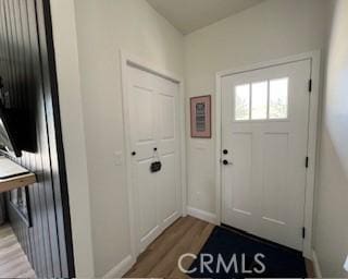 doorway with baseboards and light wood-style flooring