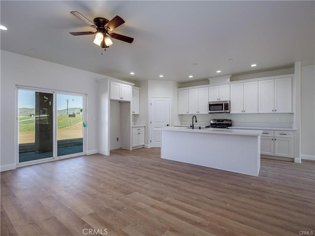 kitchen with baseboards, light wood-type flooring, white cabinets, a sink, and stainless steel appliances