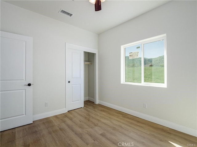 unfurnished bedroom featuring ceiling fan, baseboards, wood finished floors, visible vents, and a closet