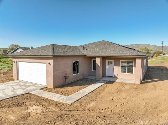 view of front of house with driveway, a shingled roof, a mountain view, and a garage