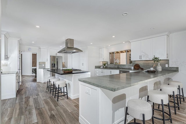 kitchen featuring a breakfast bar area, white cabinetry, and island exhaust hood