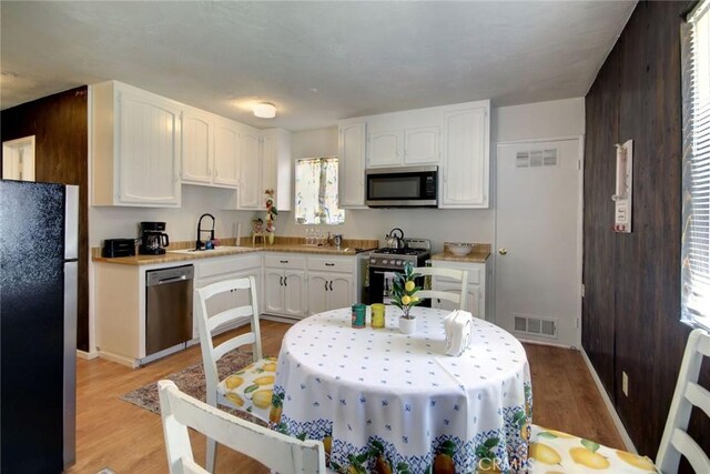 133 Holmes Ln, Sugarloaf, CA 92386 - kitchen with a sink, light wood-style flooring, stainless steel appliances, white cabinetry, and visible vents