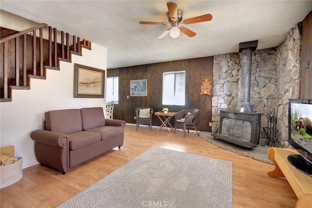 133 Holmes Ln, Sugarloaf, CA 92386 - living area with a wood stove, wood finished floors, wooden walls, stairway, and a ceiling fan