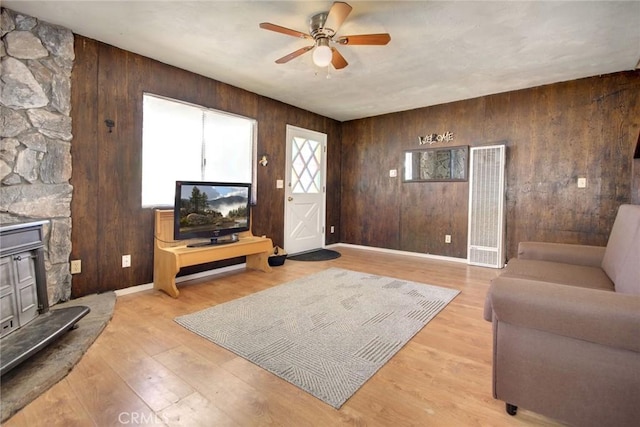 133 Holmes Ln, Sugarloaf, CA 92386 - living area featuring a heating unit, a wood stove, ceiling fan, wooden walls, and light wood-style flooring