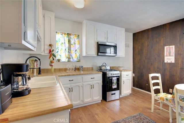 133 Holmes Ln, Sugarloaf, CA 92386 - kitchen featuring butcher block countertops, a sink, white cabinets, stainless steel appliances, and light wood-style flooring