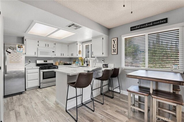 12546 Snapping Turtle Rd, Apple Valley, CA 92308 - kitchen featuring stainless steel appliances, a peninsula, light wood finished floors, a sink, and a textured ceiling