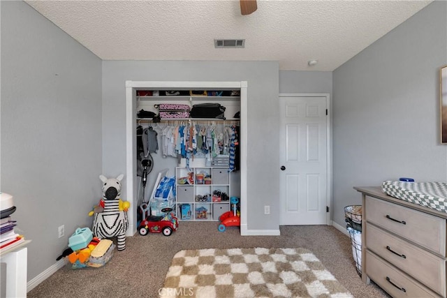 carpeted bedroom with ceiling fan, a textured ceiling, visible vents, baseboards, and a closet