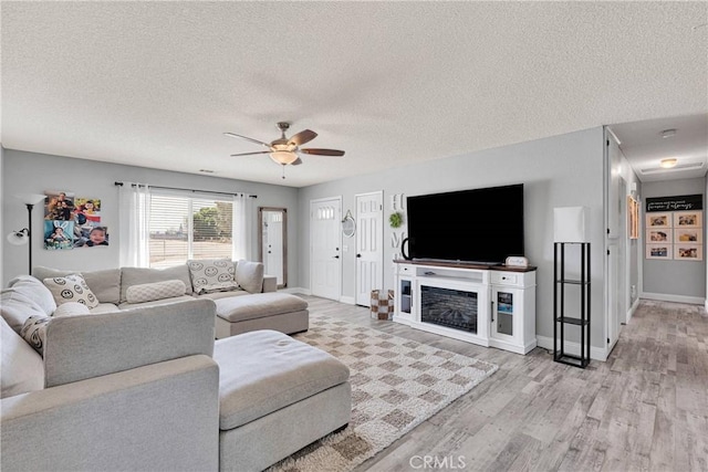 12546 Snapping Turtle Rd, Apple Valley, CA 92308 - living room with wood finished floors, a ceiling fan, a textured ceiling, baseboards, and a fireplace