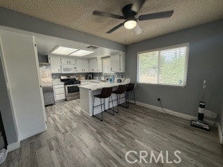 12546 Snapping Turtle Rd, Apple Valley, CA 92308 - kitchen with stainless steel range with gas cooktop, white microwave, a peninsula, a textured ceiling, and wood finished floors