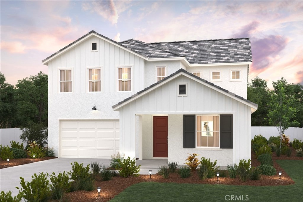 modern inspired farmhouse with board and batten siding, driveway, a lawn, fence, and an attached garage