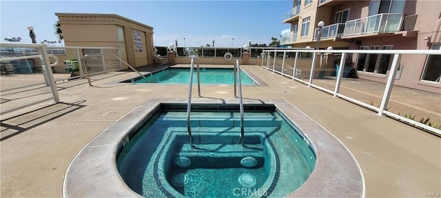 community pool featuring a community hot tub and a patio area