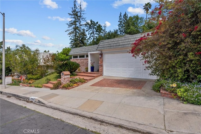 view of front of home featuring brick siding, a garage, mansard roof, and decorative driveway