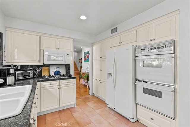 kitchen with recessed lighting, dark countertops, a sink, and white appliances