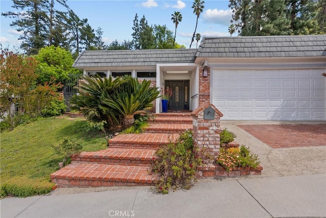 ranch-style home featuring an attached garage, a front lawn, mansard roof, and decorative driveway