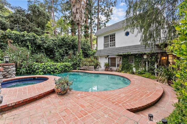 outdoor pool with a patio and an in ground hot tub