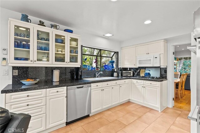 kitchen with a sink, decorative backsplash, stainless steel appliances, and white cabinetry