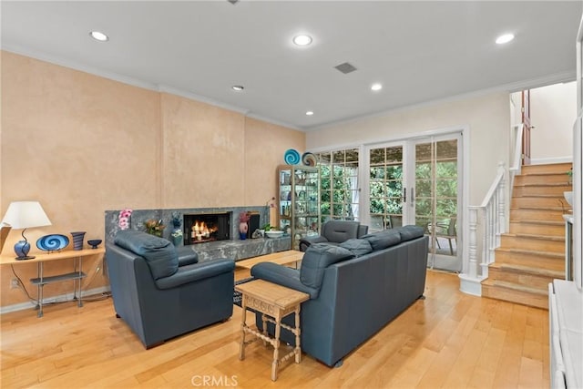 living area featuring ornamental molding, stairway, light wood-type flooring, recessed lighting, and a high end fireplace