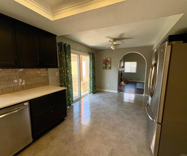 kitchen with arched walkways, appliances with stainless steel finishes, a healthy amount of sunlight, and light countertops