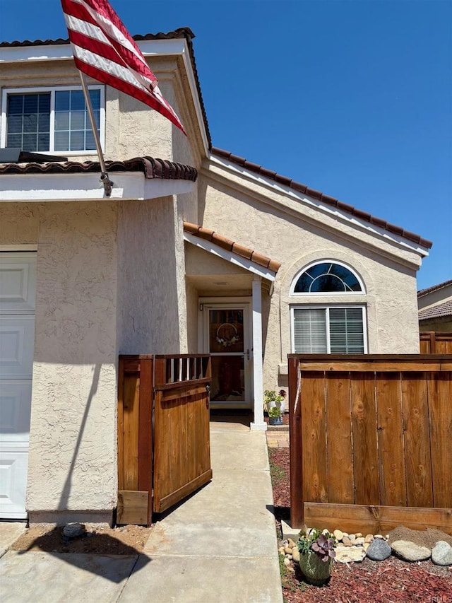property entrance with stucco siding and a tile roof