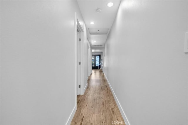 corridor featuring baseboards, recessed lighting, and light wood-style flooring