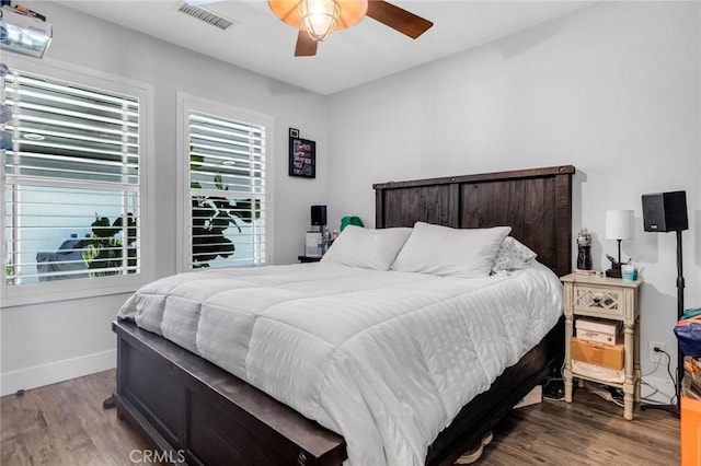 bedroom featuring visible vents, baseboards, ceiling fan, and wood finished floors