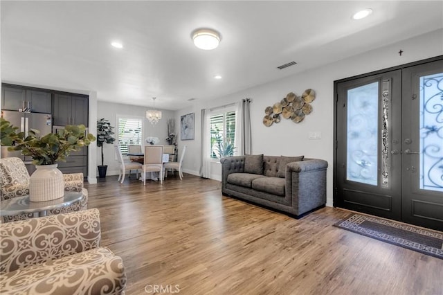 living area featuring visible vents, an inviting chandelier, wood finished floors, recessed lighting, and french doors