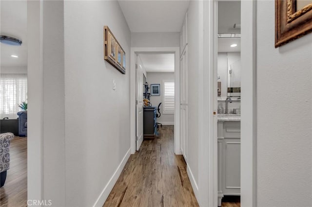 hallway with a sink, baseboards, and wood finished floors