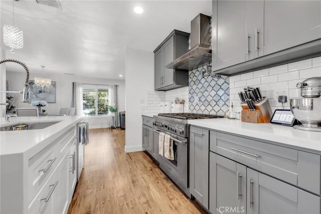 kitchen featuring wall chimney range hood, a sink, appliances with stainless steel finishes, and gray cabinets