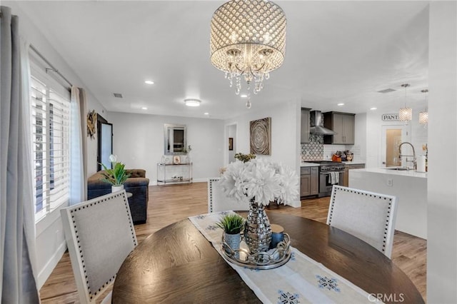 dining room with visible vents, baseboards, a notable chandelier, recessed lighting, and light wood-style flooring
