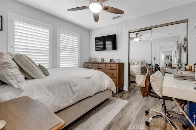 bedroom with visible vents, light wood-style floors, ceiling fan, and a closet