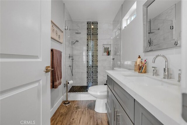 bathroom with toilet, a shower stall, wood finished floors, and vanity