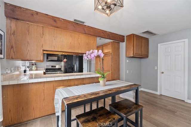 3241 Mills Ln, Crescenta, CA 91214 - kitchen featuring black appliances, tile countertops, a peninsula, brown cabinetry, and a sink