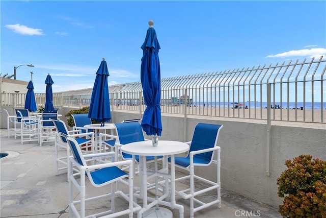 711 Pacific Coast Unit 325, Huntington Beach, CA 92648 - view of patio with a water view, fence, and outdoor dining space
