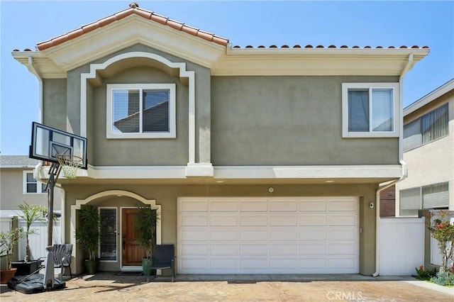 view of front facade with fence, stucco siding, an attached garage, and a tile roof